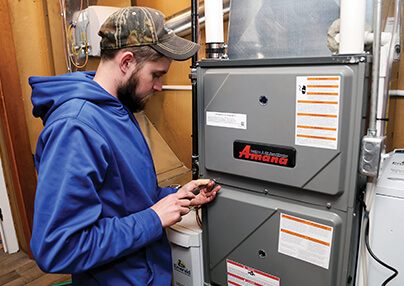 A technician unscrewing a pannel on a furnace.