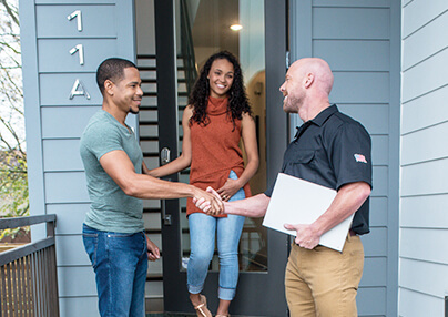 A technician shaking hands with a client leaving their home.