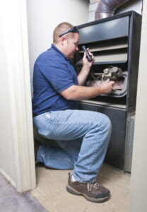 Technician inspecting and working on a furnace.