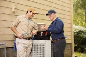 two-HVAC-technicians-inspecting-AC-cabinet