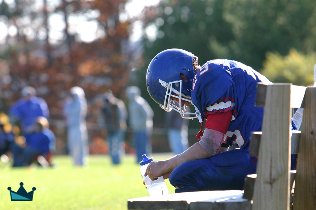 Football player sits on the bench exhausted